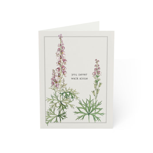Greeting card with floral design and text 'you never walk alone' on a white background