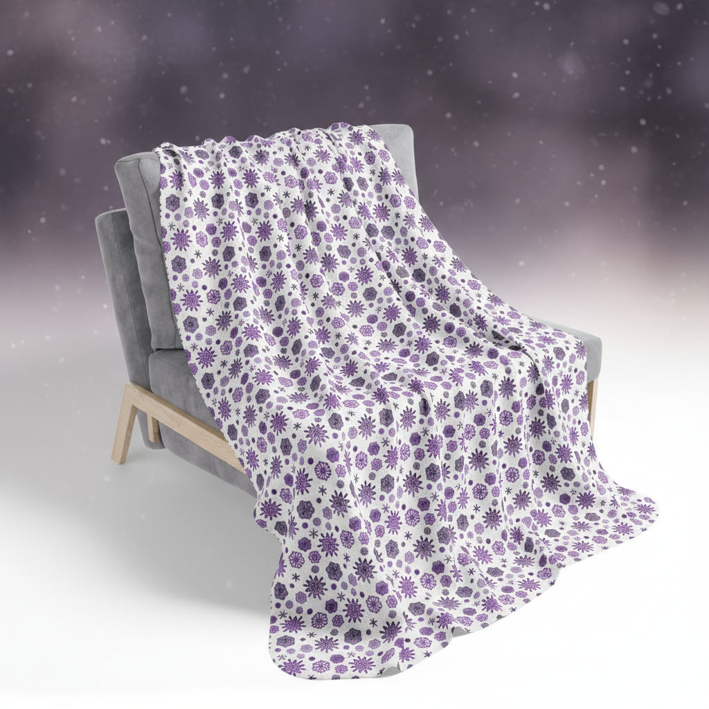 Snowflake-patterned blanket draped over a chair in a snowy landscape